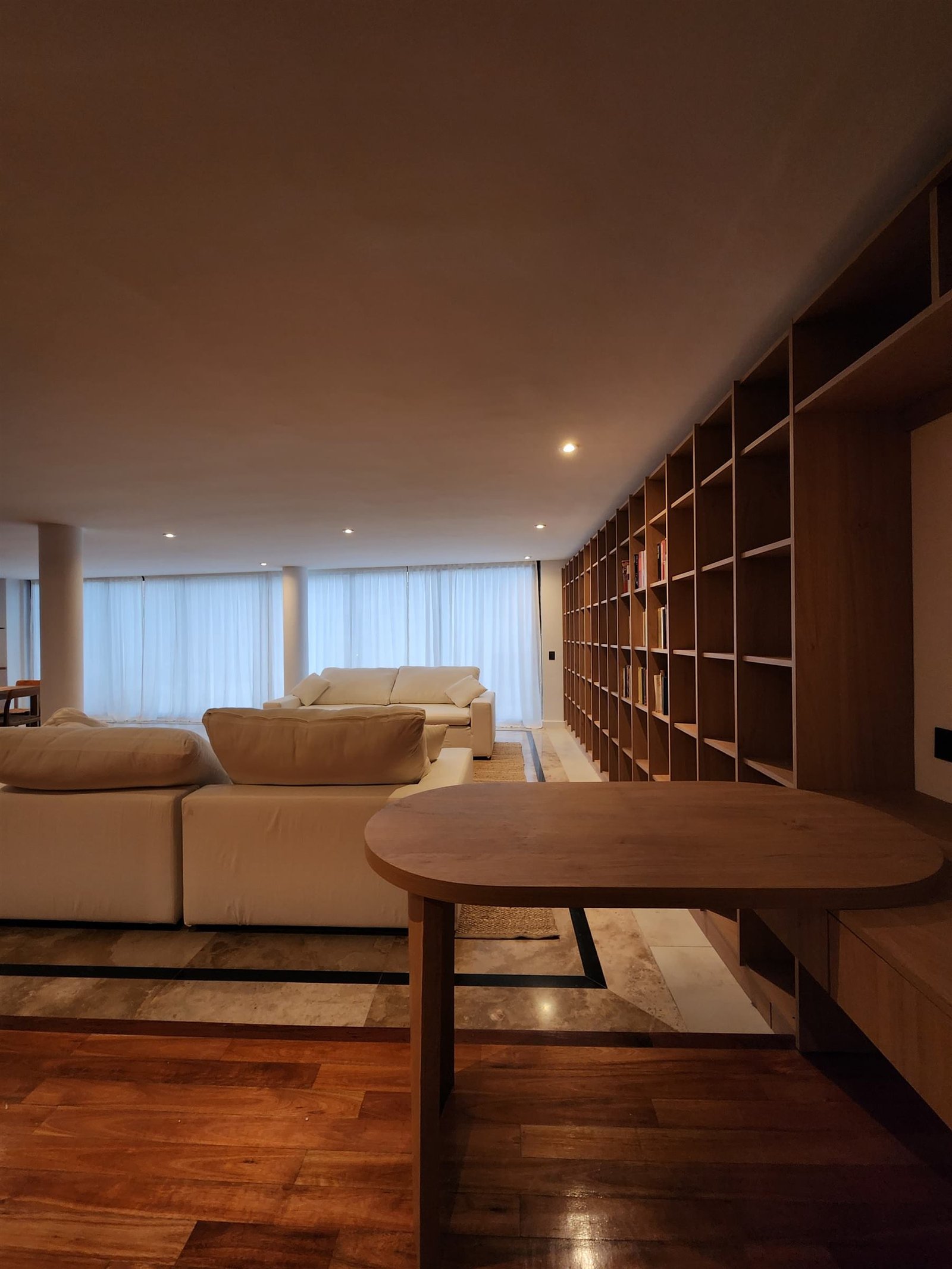 Detalle de biblioteca de madera junto a sofás blancos
