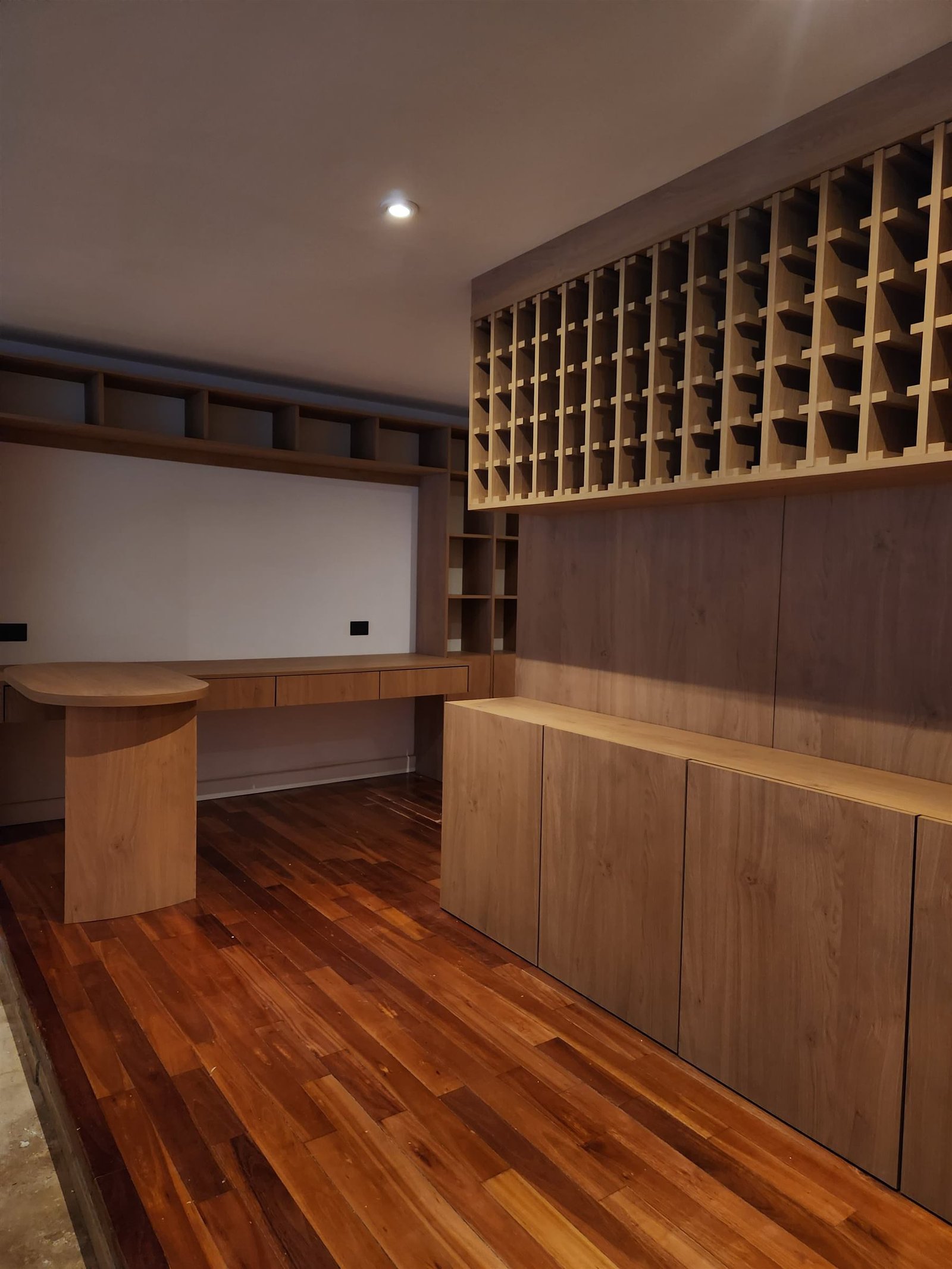 Cava de vinos, escritorio y biblioteca en madera integrados en la misma pared